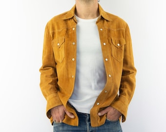 Peut inclure: Un homme portant une chemise en daim marron avec un t-shirt blanc en dessous et un jean bleu.