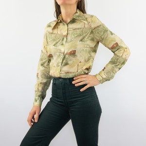 May include: A long-sleeved, light green and brown patterned shirt with a collared neckline. The shirt has a button-up front and a relaxed fit.