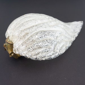 May include: A clear glass light fitting with a textured, rippled surface. The fitting has a brass base with a screw-on cap.