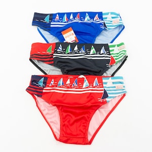 Puede incluir: Tres pares de bañadores con estampado de velero. Los bañadores son rojo, negro y azul.