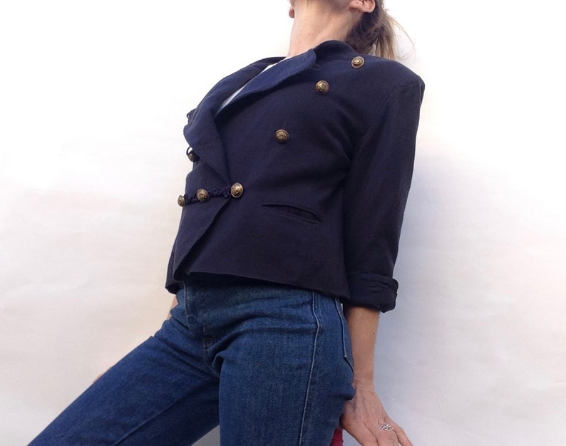 Pode incluir: Um blazer azul marinho com fecho de dupla abotoadura e bot&otilde;es dourados. O blazer tem colarinho e mangas compridas.