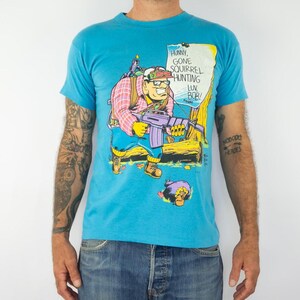 SSI | Vintage Cartoon Tee-Shirt | 1990s | Macho Earth Natives | Hunting Comic Tee | Single Stitch | Blue Soft Cotton | Made in USA | Size M