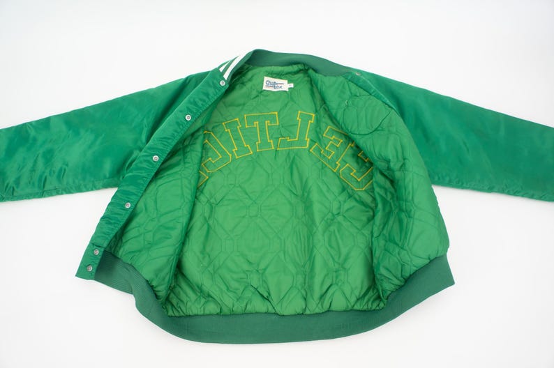 May include: Green satin varsity jacket with a quilted lining and "CELTICS" embroidered in yellow on the inside.