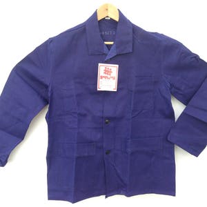 May include: A dark blue work jacket with a button closure and two large pockets on the front. The jacket has a label with the text "SPRZEDAŻ" on it.