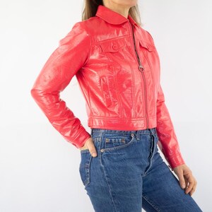 May include: A bright red cropped leather jacket with a zipper closure and a collared neckline.