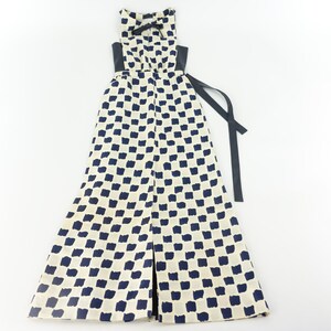 May include: A white maxi dress with a black and white checkered pattern. The dress has a black sash that ties at the waist.