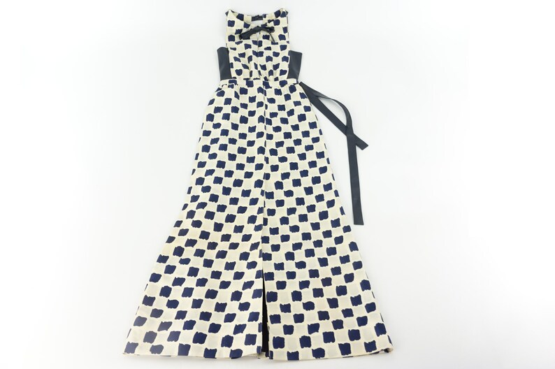 May include: A white maxi dress with a black and white checkered pattern. The dress has a black sash that ties at the waist.