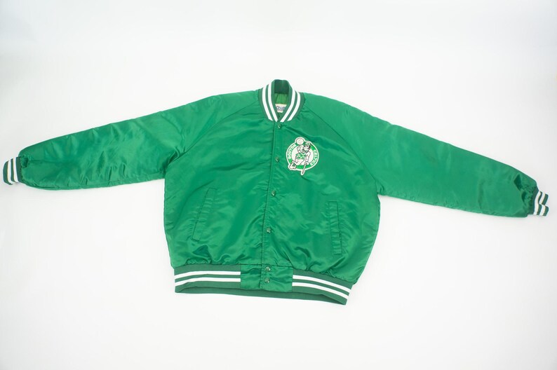 May include: Green satin bomber jacket with white and green striped cuffs and waistband. The jacket features a large Boston Celtics logo on the front.