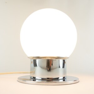 May include: A white globe lamp with a chrome base and a round chrome base.