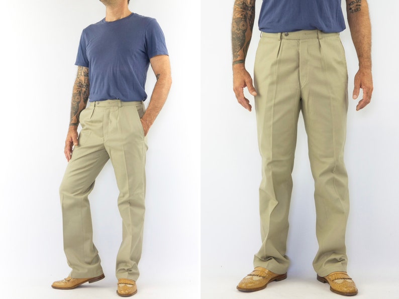 May include: A pair of beige pleated pants with a straight leg fit. The pants have a button and zipper closure and belt loops.