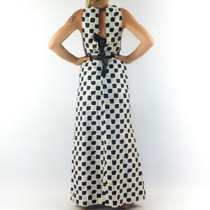 May include: A white maxi dress with a black and white checkered pattern. The dress has a sleeveless design and a tie at the back.