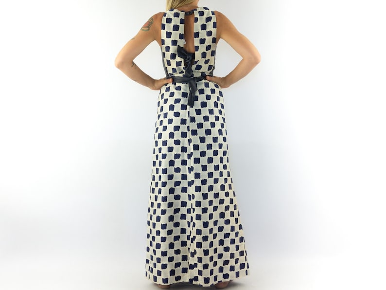 May include: A white maxi dress with a black and white checkered pattern. The dress has a sleeveless design and a tie at the back.