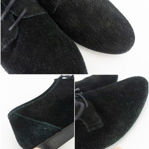 Op de afbeelding: Een paar zwarte su&egrave;de veterschoenen met een geperforeerd ontwerp. De schoenen hebben een ronde neus en een lage hak.
