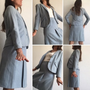 Puede incluir: Un traje de falda azul claro a rayas finas, compuesto por una chaqueta y una falda. El traje est&aacute; hecho de una tela ligera y tiene un corte cl&aacute;sico y entallado.