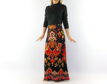 May include: A long black maxi dress with a colorful floral print. The dress has a mock neck and long sleeves. The skirt portion of the dress is a vibrant red, orange, and yellow floral pattern on a black background.