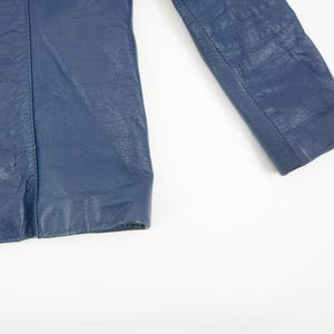 K&ouml;nnte beinhalten: Nahaufnahme eines Teils einer marineblauen Lederjacke. Das Bild zeigt die strukturierte Oberfl&auml;che des Leders und die Nahtdetails. Die Jacke scheint im Vintage- oder Retro-Stil zu sein.