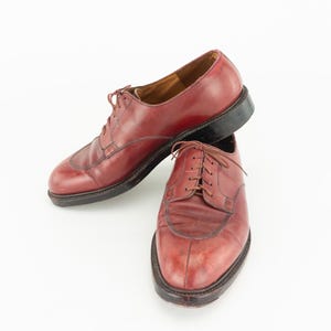 May include: A pair of burgundy leather lace-up shoes. The shoes have a pointed toe and a low heel.