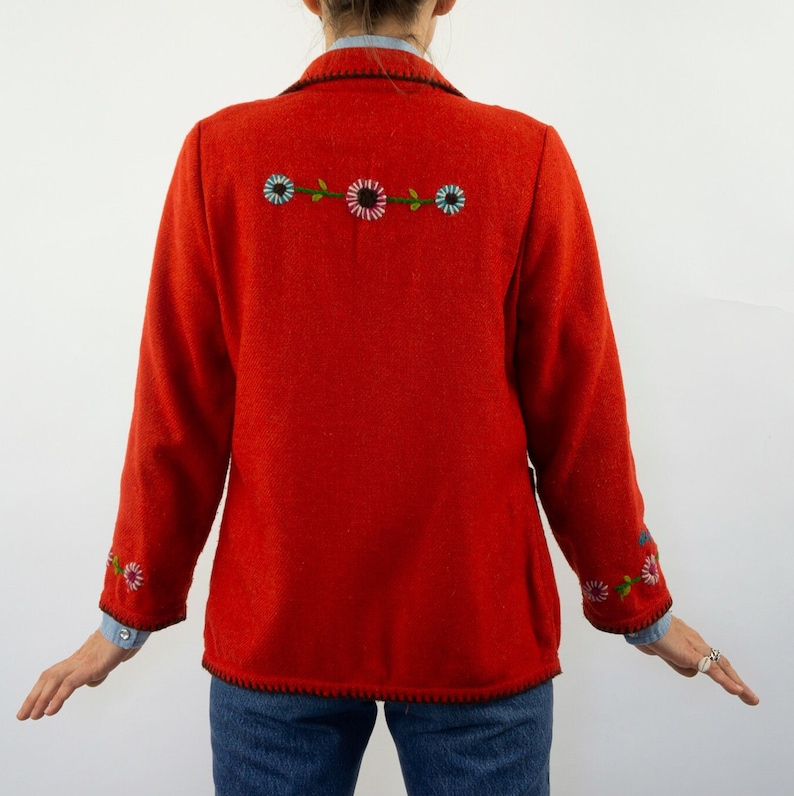 May include: A red wool blazer with embroidered flowers on the back and sleeves. The blazer has a black trim around the edges.
