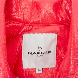 May include: Close-up of a bright pink leather jacket with a white label that reads "N by Naf Naf Paris" and "38".