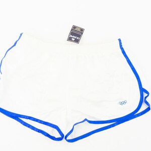 May include: White athletic shorts with blue trim and the Olympic rings logo. The shorts have a drawstring waist and are made of a lightweight fabric.