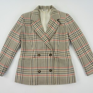 Pu&ograve; includere: Un blazer doppiopetto con motivo a quadri beige, rossi e neri. La giacca ha due tasche anteriori e bottoni marroni. La fodera &egrave; di colore crema.