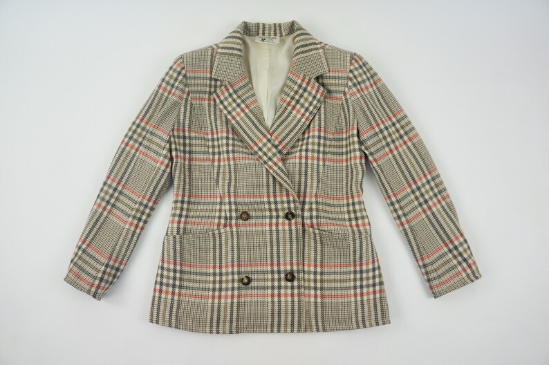Pu&ograve; includere: Un blazer doppiopetto con motivo a quadri beige, rossi e neri. La giacca ha due tasche anteriori e bottoni marroni. La fodera &egrave; di colore crema.