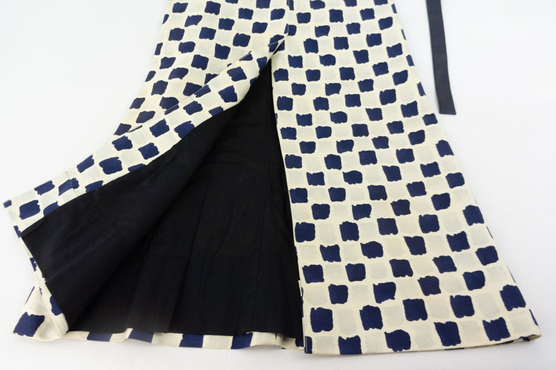 May include: A white skirt with a blue and white checkered pattern. The skirt has a slit up the front and a black belt.