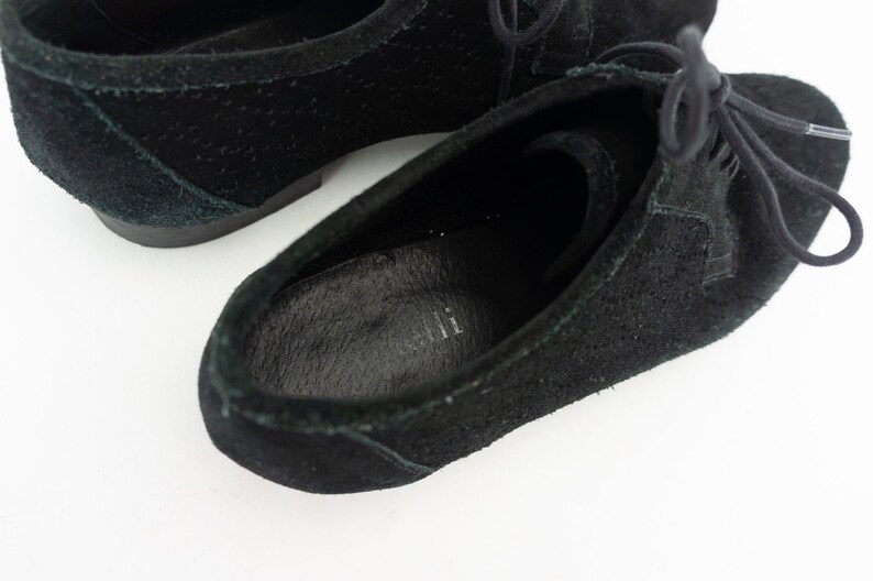 Op de afbeelding: Een paar zwarte su&egrave;de veterschoenen. De schoenen hebben een lage hak en een ronde neus.