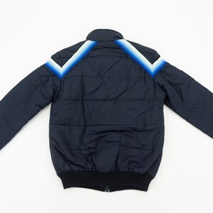 May include: A navy blue puffer jacket with a white and blue striped design on the shoulders.