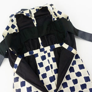 May include: A white and blue checkered dress with black straps and a black lining. The dress has a low back and is open in the front.