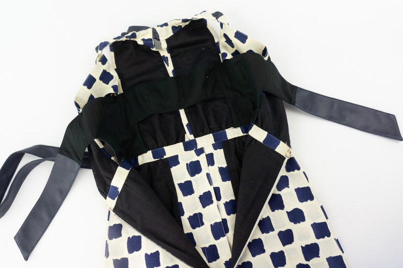 May include: A white and blue checkered dress with black straps and a black lining. The dress has a low back and is open in the front.