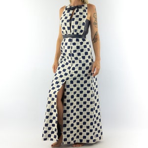 May include: A white maxi dress with a black belt and a blue and white checkered pattern. The dress has a keyhole neckline and a slit up the front.