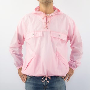 May include: A pink hooded jacket with a drawstring waist and two pockets. The jacket has a lace-up closure at the neck.