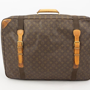 May include: A brown and tan vintage Louis Vuitton suitcase with a monogram pattern and leather straps.