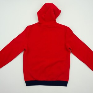K&ouml;nnte beinhalten: Roter Kapuzenpullover mit einem marineblauen Saum an Kapuze, &Auml;rmelb&uuml;ndchen und Unterkante.