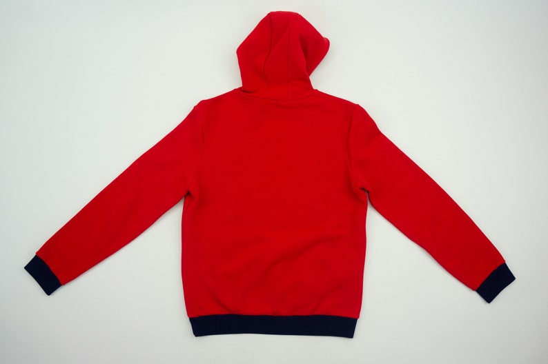 K&ouml;nnte beinhalten: Roter Kapuzenpullover mit einem marineblauen Saum an Kapuze, &Auml;rmelb&uuml;ndchen und Unterkante.