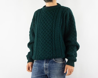 May include: A dark green cable knit sweater with a crew neck.