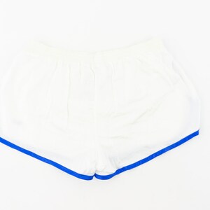 May include: White athletic shorts with a blue trim around the edges.