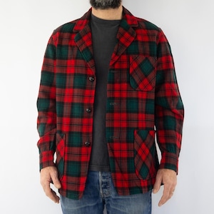 Peut inclure: Une veste en plaid rouge et vert avec un devant boutonné et deux grandes poches. La veste a une coupe décontractée et ample.