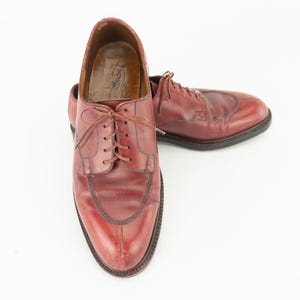 May include: A pair of brown leather lace-up shoes with a wingtip design. The shoes have a polished finish and are in good condition.