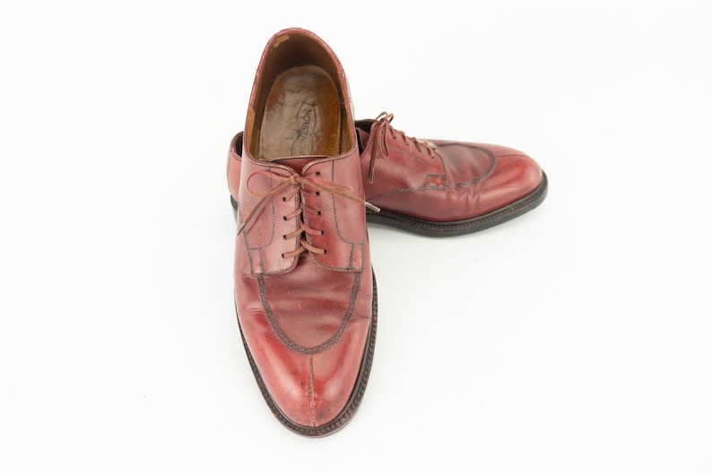 May include: A pair of brown leather lace-up shoes with a wingtip design. The shoes have a polished finish and are in good condition.