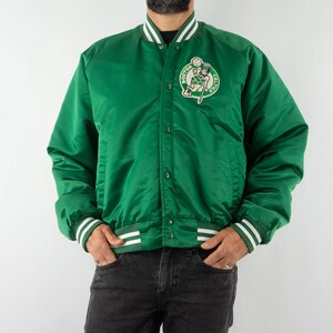 May include: A green satin bomber jacket with white and green striped ribbing at the cuffs and collar. The jacket features a large embroidered patch on the left chest with the Boston Celtics logo.