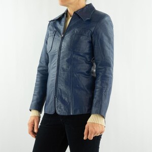 K&ouml;nnte beinhalten: Eine marineblaue Vintage-Lederjacke mit Kragen, zwei Brusttaschen und einem durchgehenden Rei&szlig;verschluss. Die Jacke hat lange &Auml;rmel und wird mit einer schwarzen Hose getragen. Die Jackenl&auml;nge betr&auml;gt ca. 71 cm.
