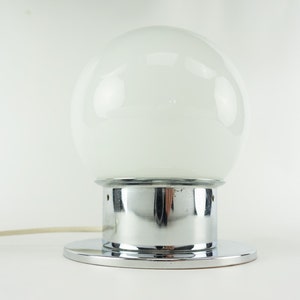 May include: A chrome table lamp with a white glass globe shade.