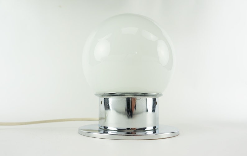 May include: A chrome table lamp with a white glass globe shade.