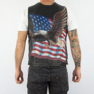 May include: A black leather vest with a printed image of an American bald eagle flying over an American flag.