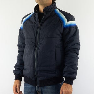 May include: A navy blue puffer jacket with a zipper closure and a striped design on the shoulders. The stripes are in shades of blue and white.