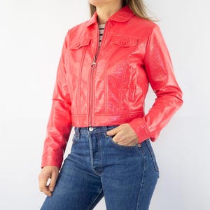 May include: A bright red cropped leather jacket with a zipper closure and two flap pockets.