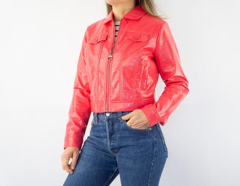 May include: A bright red cropped leather jacket with a zipper closure and two flap pockets.