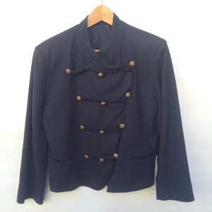Pode incluir: Um blazer azul marinho com gola mandarim e bot&otilde;es dourados. O blazer tem um design assim&eacute;trico &uacute;nico com uma &uacute;nica fila de bot&otilde;es de um lado e uma dupla fila do outro.